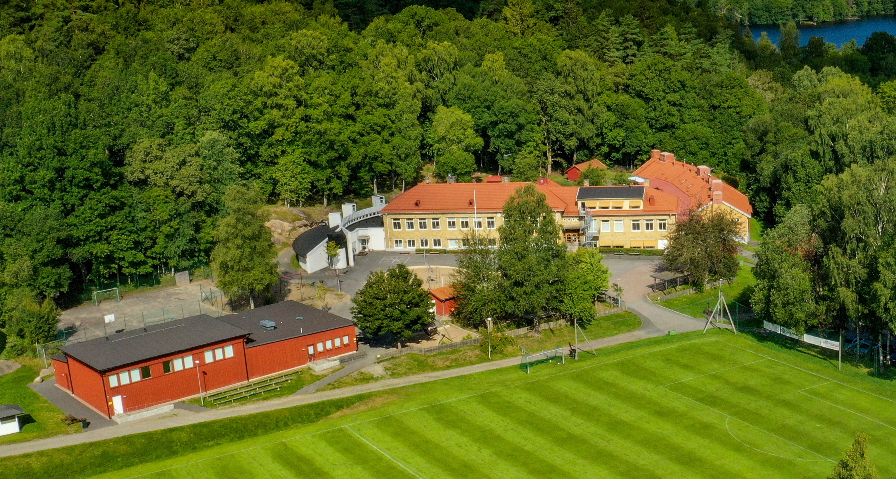 En bild från luften över skolans byggnader. Runtom är det en fotbollsplan och skog.