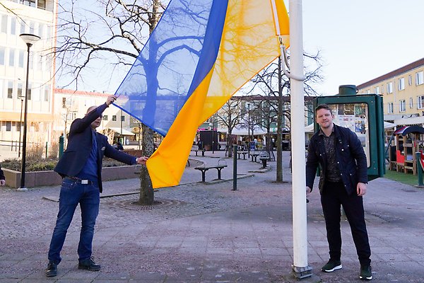 Kommunstyrelsens ordförande och kommunens säkerhetschef hissar en ukrainsk flagga på Bagges Torg i centrala Lerum.